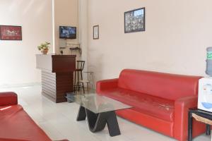 a living room with a red couch and a table at Al-Ghani Syariah Mitra RedDoorz in Padang