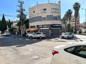 a street with cars parked in front of a building at Nazarena Studio Apartment in Nazareth