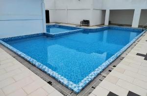 una gran piscina de agua azul en un edificio en Homestay Studio Apartment Bentara Suite, Kompleks Mutiara Gua Musang, en Gua Musang