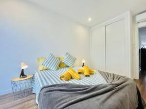 a bedroom with a bed with yellow towels on it at Limoeiro - Shopping Center 50m - Modern in Portimão