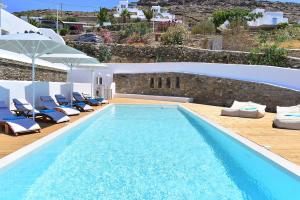 a swimming pool with chaise lounge chairs and a villa at Horizon Villas in Agios Ioannis