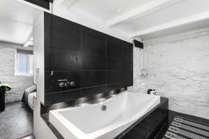 a large white tub in a bathroom with black tiles at Baron Downtown Apartments in Reykjavík +49 photos