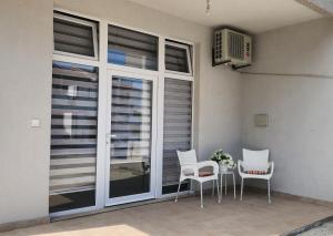 a patio with white chairs and a table and windows at Maria in Igalo