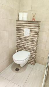 a bathroom with a toilet with a wooden wall at Maria in Igalo