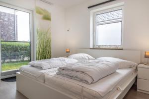 1 dormitorio blanco con 1 cama y 2 ventanas en 50079..., en Carolinensiel