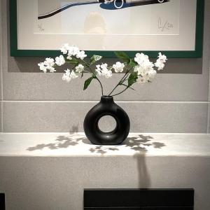 a black vase with white flowers sitting on a table at Stylish Urban Retreat In West London in Brentford