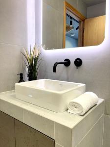 a white sink in a bathroom with a mirror at Stylish Urban Retreat In West London in Brentford