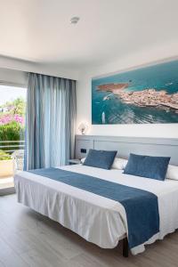 una camera da letto con un grande letto e un dipinto sul muro di Hospedium Hotel Abril a San Juan de Alicante