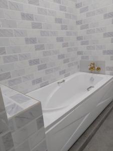 een wit bad in een badkamer met een tegelwand bij MT HOMESTAY in Alor Setar