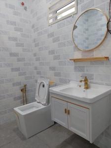 een badkamer met een wastafel, een toilet en een spiegel bij MT HOMESTAY in Alor Setar