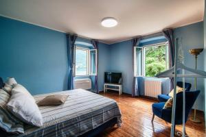 a blue bedroom with a bed and a chair at Lemon Tree Lake View - by MyHomeInComo in Laglio