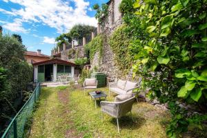 a garden with two chairs and a couch and a table at Lemon Tree Lake View - by MyHomeInComo in Laglio