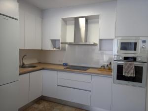 a white kitchen with a sink and a microwave at Apartamento El Ingenio in Adra