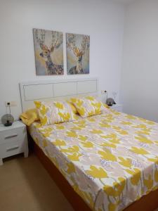 a bedroom with a bed with a yellow and white comforter at Apartamento El Ingenio in Adra