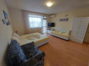 a living room with two beds and a tv at Primorski Briz Guest House in Primorsko