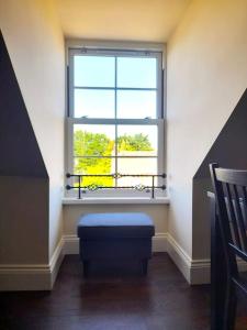 a room with a window and a blue ottoman in front thereof at Kirkcudbright Holiday Apartments - Apartment G in Kirkcudbright