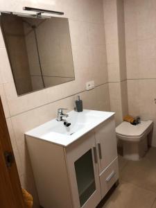 a bathroom with a sink and a mirror and a toilet at Apartamento El Ingenio in Adra