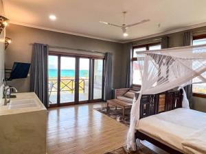 a bedroom with a bed and a bathroom with a balcony at Aquamarina Hotel & Villas in Jambiani