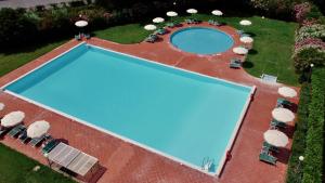 uma vista sobre uma grande piscina com cadeiras em Le Residenze di Santa Costanza - Il Lentisco em San Vincenzo