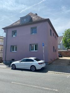 ein weißes Auto, das vor einem rosa Haus parkt in der Unterkunft Ferienwohnung Susan-Nur 10 Fahrminuten von Playmobil in Zirndorf