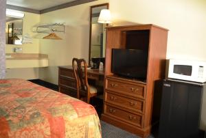 a hotel room with a bed and a desk with a television at Economy Inn Bluefield in Bluefield