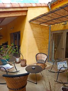 eine Terrasse mit Stühlen, einem Tisch und einer Pergola in der Unterkunft Ô Rêves Ailleurs in Saint-Cyr-sur-Mer