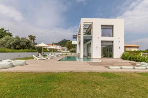 a white house with a swimming pool and some chairs at Armonia Luxury Villa in Triánta