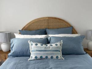 a bed with blue and white pillows on it at Seaview Treehouse - three minute walk to the beach in Lorne