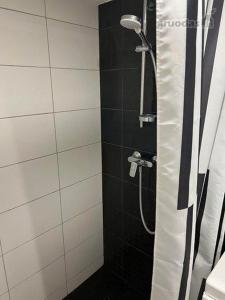 a bathroom with a shower with a black and white at Lofto tipo 2 kambarių butas in Kaunas