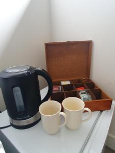 dos tazas de café en un mostrador junto a una caja en Een klein appartementje zonder keuken in het centrum Sleep at Hamtingh's en Hilvarenbeek