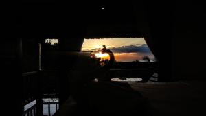 a person is looking out a window at the sunset at Vina Bungalow in Toyapakeh