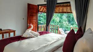 a bedroom with a bed with a large window at Vina Bungalow in Toyapakeh
