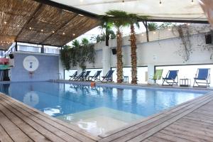 a large swimming pool with chairs and palm trees at Hamra Urban Gardens in Beirut
