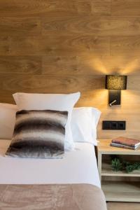 1 dormitorio con 1 cama y pared de madera en Acta Arthotel en Andorra la Vella