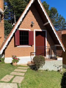 a brick house with a red door and a porch at Chalés Paraíso Monte Verde in Monte Verde