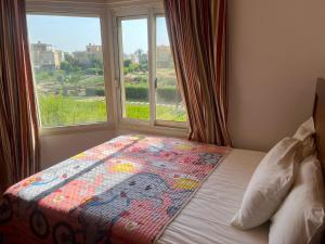 a bed with a quilt on it in front of a window at A sea view spacious cheering 5 bedroom villa Ain Sokhna "Ain Bay" فيلا كاملة للإيجار قرية العين باي in Ain Sokhna
