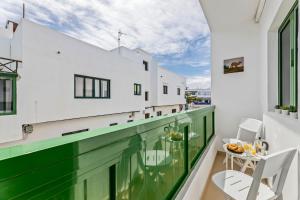 Home2Book Charming Apartment Tinajo, Wifi في لا سانتا: شرفة بجدران خضراء وبيضاء وطاولة وكراسي