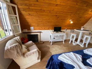 a living room with a couch and a desk with a computer at Chalés Paraíso Monte Verde in Monte Verde