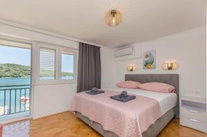 een slaapkamer met een bed met roze kussens en een balkon bij Apartment Paradise in Kaprije