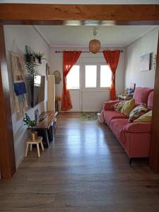 uma sala de estar com um sofá vermelho e um piso de madeira em Apartamento en Plentzia en barrio muy tranquilo con aparcamiento gratuito y al lado del metro em Elejalde