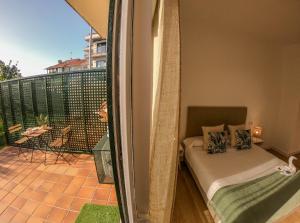 a bedroom with a bed and a balcony with a view at CostaSerenaSuites in Nigrán