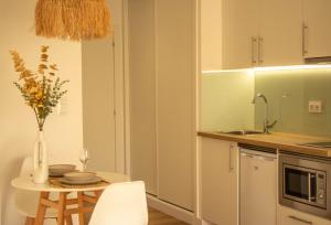 a kitchen with a table with a vase of flowers at CostaSerenaSuites in Nigrán
