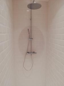 y baño de azulejos blancos con ducha y luz. en Les 3 Platanes, en Conilhac-Corbières