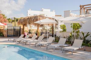 a row of white chairs and umbrellas next to a swimming pool at Dormio Resort Costa Blanca Beach & Spa in El Campello
