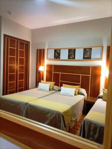 een slaapkamer met 2 bedden en 2 ramen bij Hotel Carmen in La Carlota