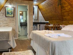 a bedroom with two beds and a kitchen with a table at Chalés Paraíso Monte Verde in Monte Verde