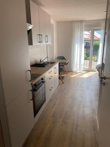 cocina con armarios blancos y suelo de madera en Obstbau Apartment am See en Lindau
