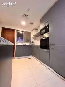 cocina con electrodomésticos de acero inoxidable y suelo de baldosa en One Bed Room Apartment Muscat Hills en Mascate