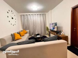 a living room with a white couch and yellow pillows at One Bed Room Apartment Muscat Hills in Muscat