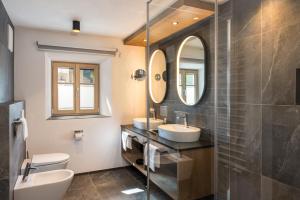 a bathroom with two sinks and two mirrors at Adlhof Apartments in Brunico +48 photos